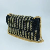 Black clutch purse with gold chain strap and gold studded embellishments on white background