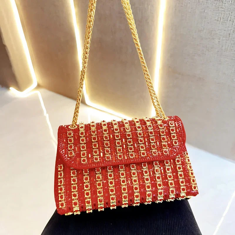 Red evening handbag with gold studs and chain strap on a white surface