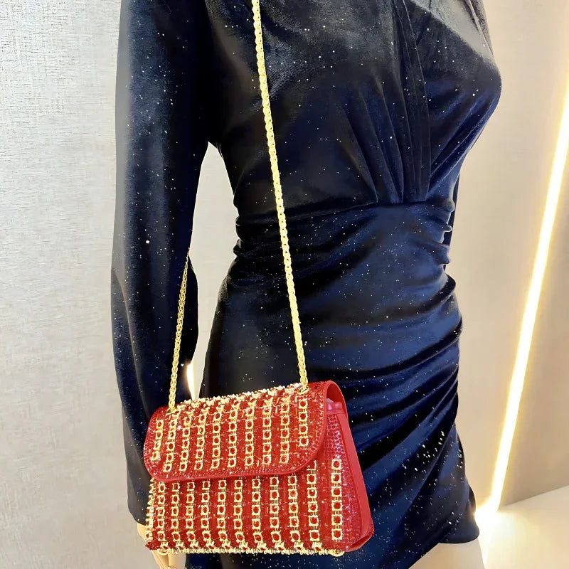 Red chain-embellished purse with gold strap on mannequin in a fitted black dress