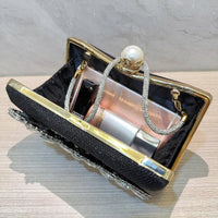 Black clutch purse with gold trim, pearl clasp, rhinestone handle, and cosmetics inside