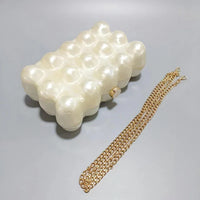 Pearl pattern clutch bag with gold chain strap on a gray surface