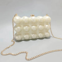 Pearl-pattern bubble clutch purse with gold chain strap on light gray background