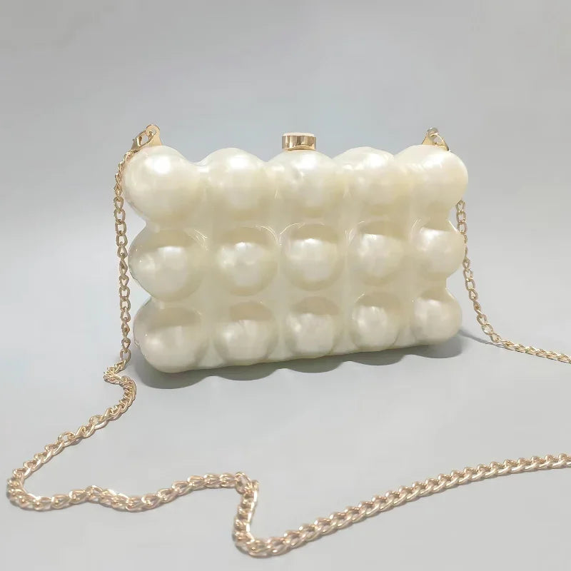 Pearl-pattern bubble clutch purse with gold chain strap on light gray background