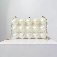 Pearl beaded evening clutch bag with gold chain on white display, fashion accessory