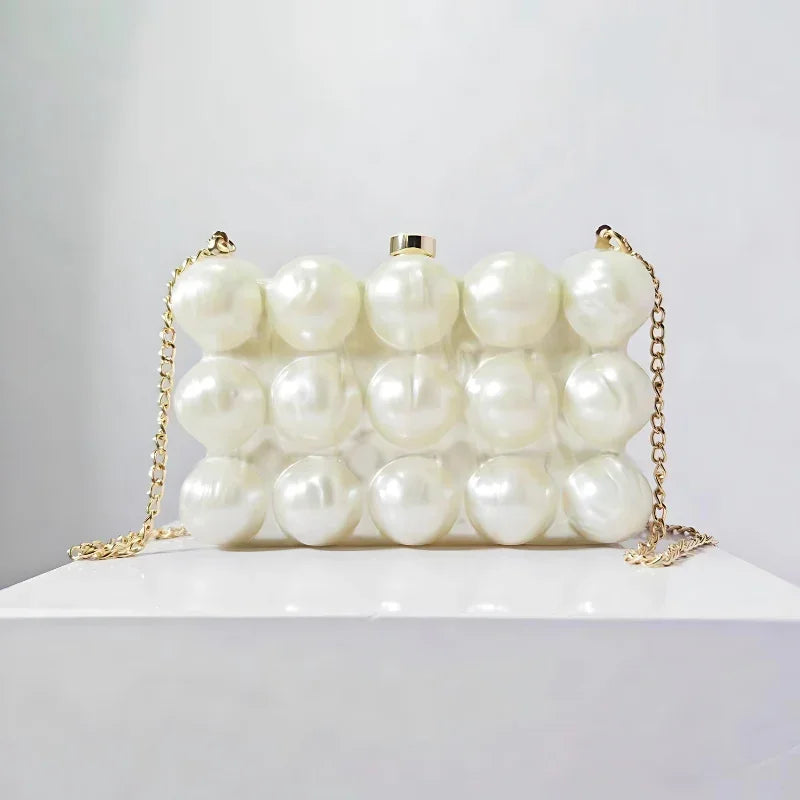 Pearl beaded evening clutch bag with gold chain on white display, fashion accessory
