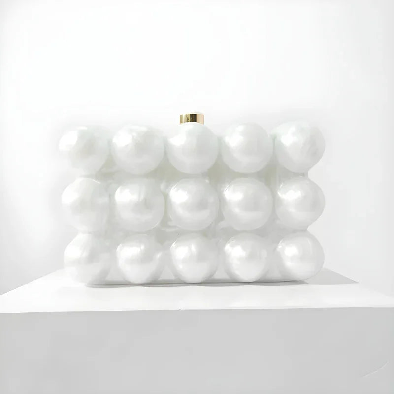 White pearl bubble clutch purse with gold clasp on white display pedestal