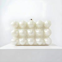 White clutch bag with raised pearl-like bubbles on display against a plain white background