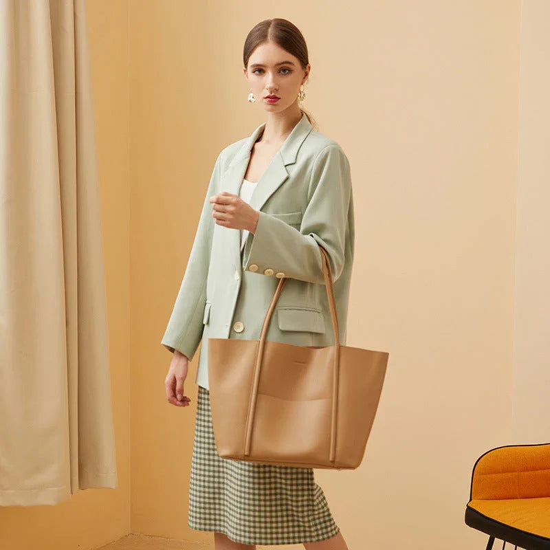 Woman in mint blazer and checkered skirt holding tan tote bag in modern room