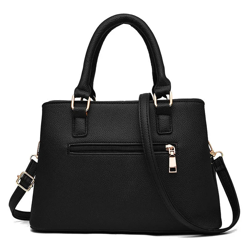 Black leather handbag with gold hardware, top handles, and detachable shoulder strap