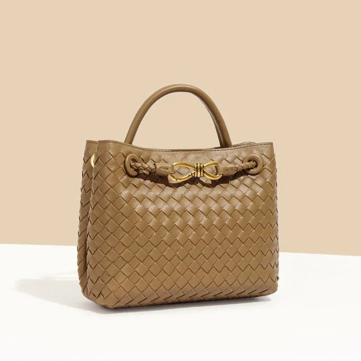 Brown woven leather handbag with gold bow accent, top handle, elegant purse on beige background