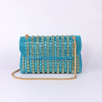 Turquoise beaded clutch bag with gold chain strap and crystal embellishments on white background