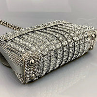 Silver crystal-studded handbag with chain strap on reflective surface