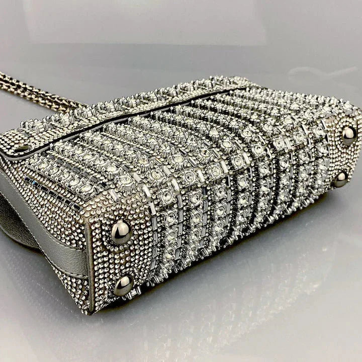 Silver crystal-studded handbag with chain strap on reflective surface