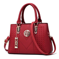 Elegant red leather handbag with gold hardware and decorative textured pattern