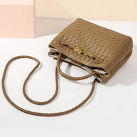 Brown woven leather crossbody bag with braided strap on white background