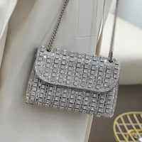 Silver rhinestone evening bag with chain strap on a white blazer