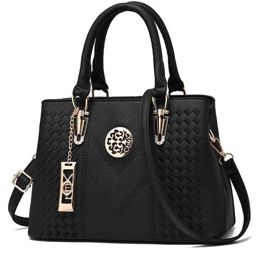 Black leather handbag with gold hardware, textured pattern, and decorative emblem