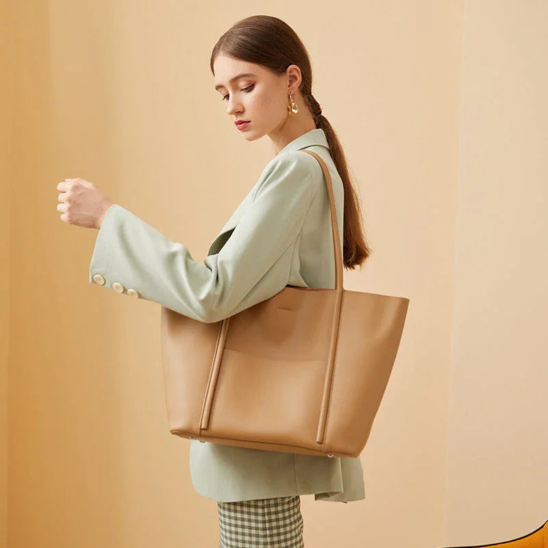 Woman in mint blazer carrying large tan leather tote bag against beige background