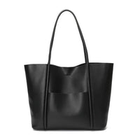 Black leather tote bag with long handles and front pocket on white background