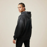 Person wearing a black hoodie with a Pitbull dog graphic on the back against a beige background | Rebooters