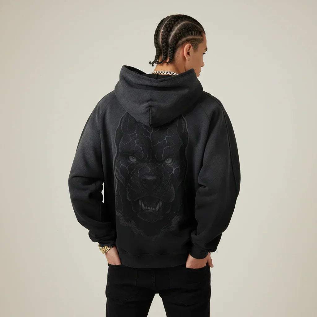 Person wearing a black hoodie with a Pitbull dog graphic on the back against a plain background | Rebooters