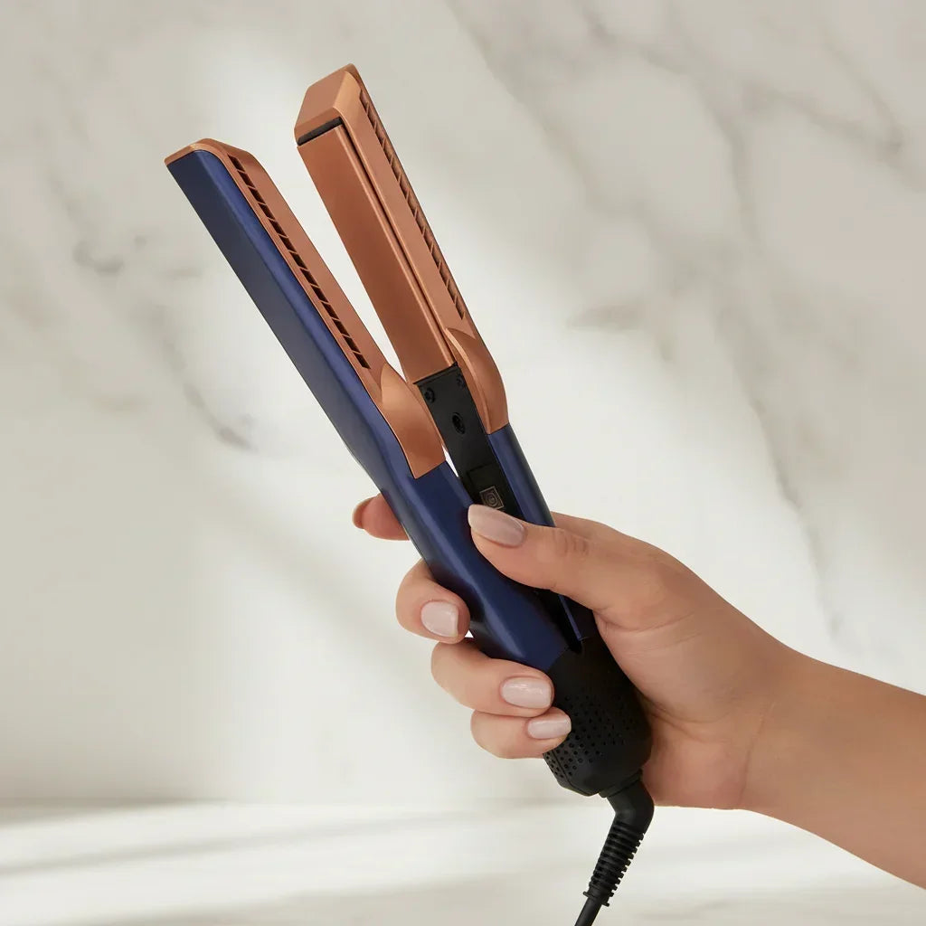 Hand holding a blue and brown hair straightener against a neutral background