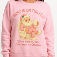 Pink sweatshirt with Santa Claus graphic and text on a white background