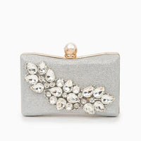 Silver clutch purse with crystal embellishments and pearl clasp on white background