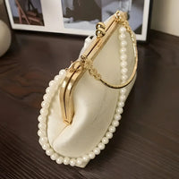 Elegant white pearl beaded handbag with gold clasp on dark wood table