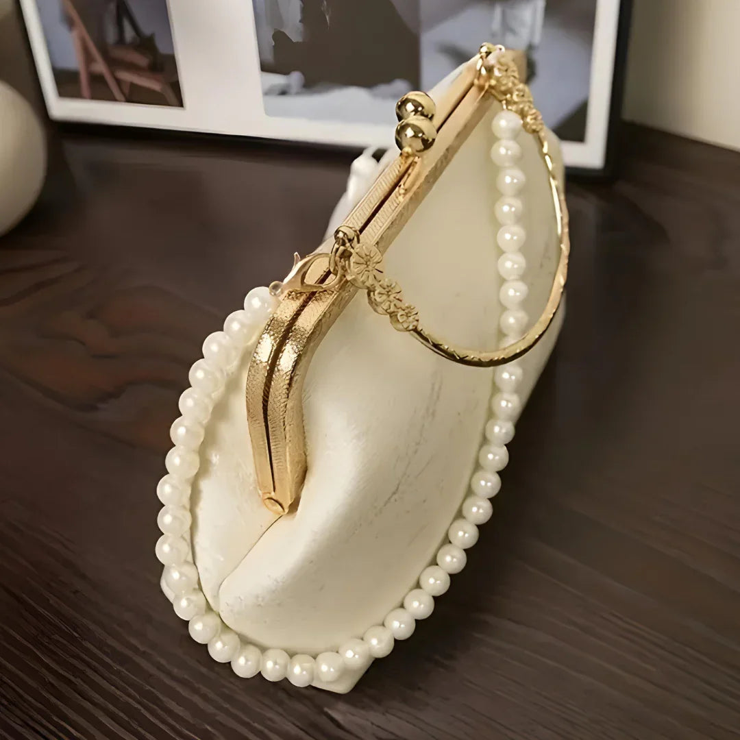 Elegant white pearl beaded handbag with gold clasp on dark wood table