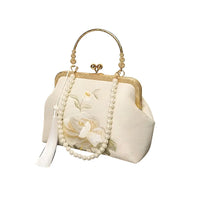 Elegant white floral purse with pearl handle, gold frame, and tassel on white background