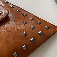 Brown leather clutch with silver square studs on white background