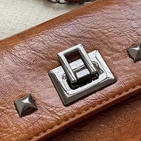 Brown leather handbag with silver turn-lock clasp and stud accents