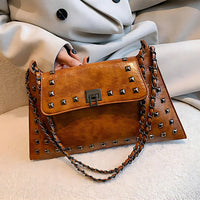 Brown leather studded handbag with chain strap and silver clasp, woman in beige coat