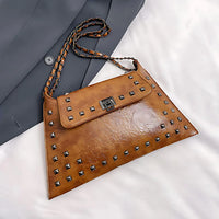 Brown leather studded clutch bag with chain strap on white and gray fabric background
