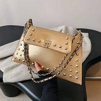Gold studded handbag with chain strap, quilted texture on black chair