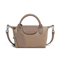 Taupe leather mini handbag with top handle, detachable strap, and luggage tag