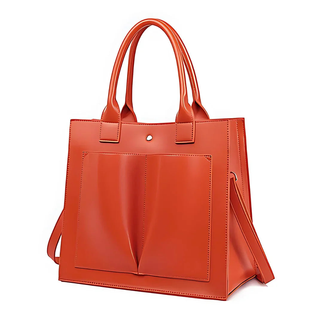 Orange leather tote bag with front pockets and top handles on a white background