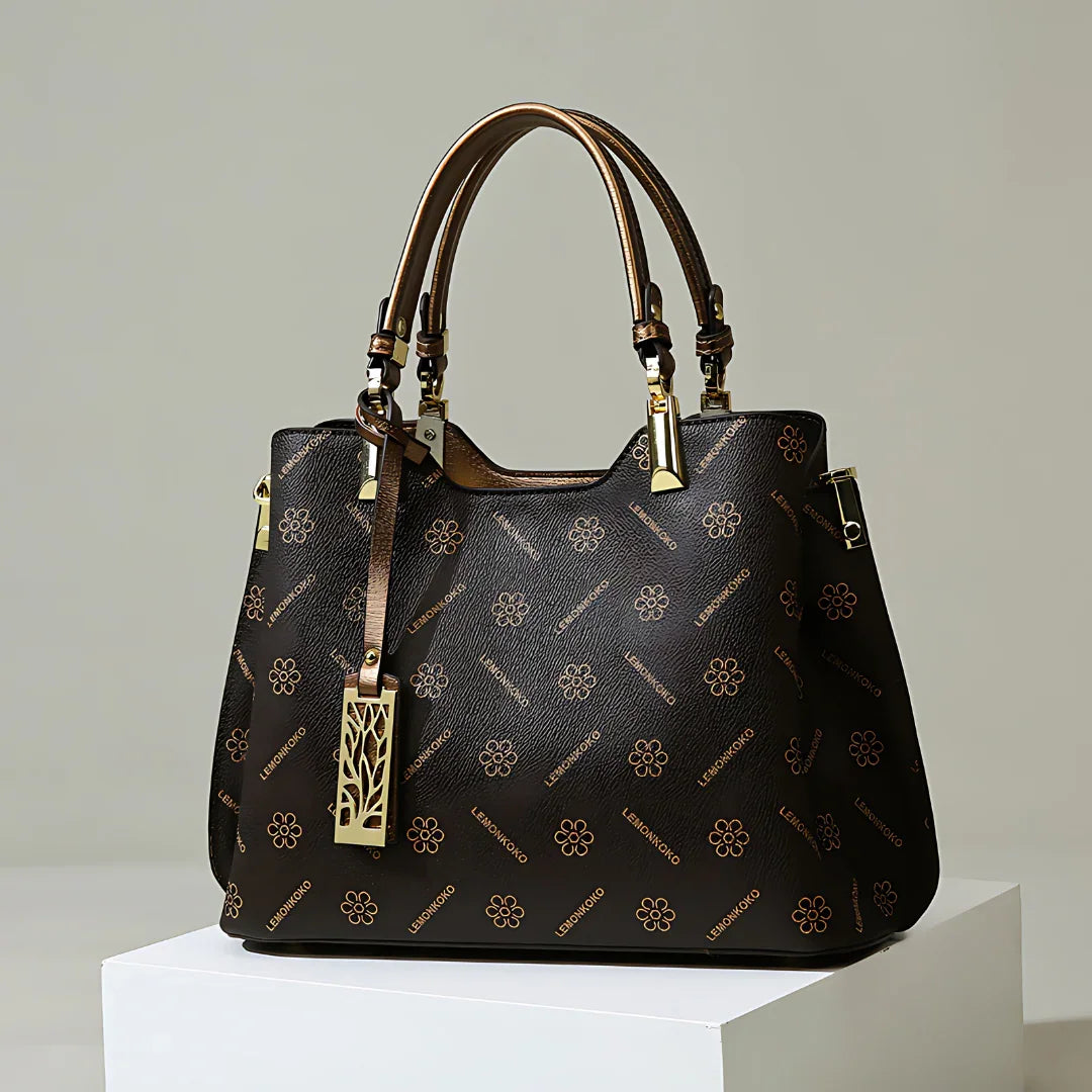 Luxury brown leather handbag with gold floral pattern and double handles on display