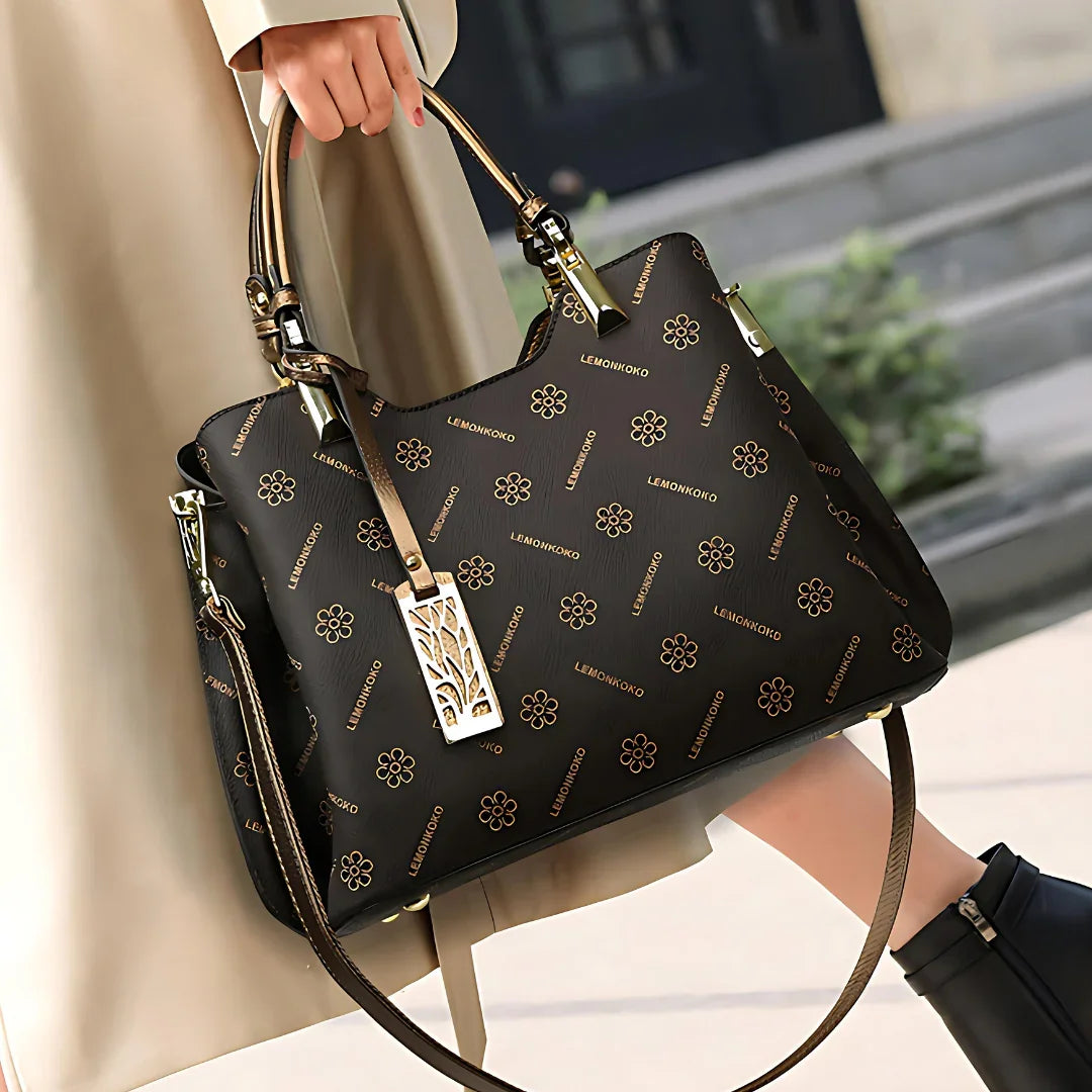 Woman holding a black LEMONKOKO designer handbag with gold floral pattern and hardware