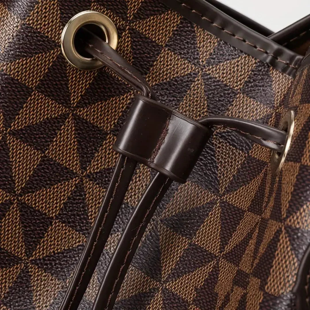 Close-up of brown geometric leather bag with gold eyelets and dark drawstring.