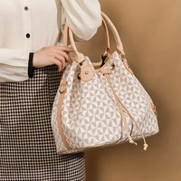 Woman holding geometric patterned bucket bag with beige leather trim