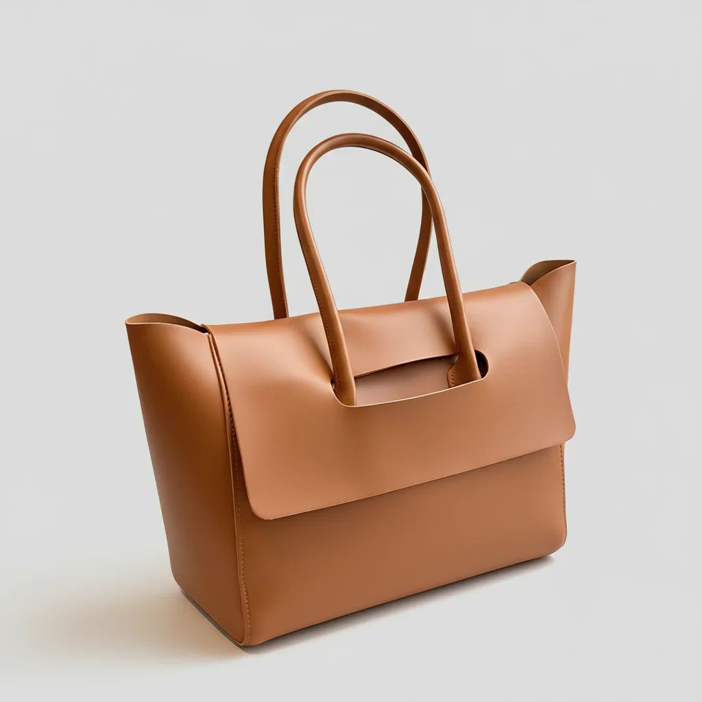 Tan leather tote bag with structured design and double handles on a plain background