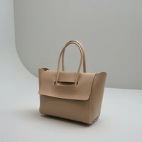 Beige leather tote handbag with top handles on a minimalist gray background