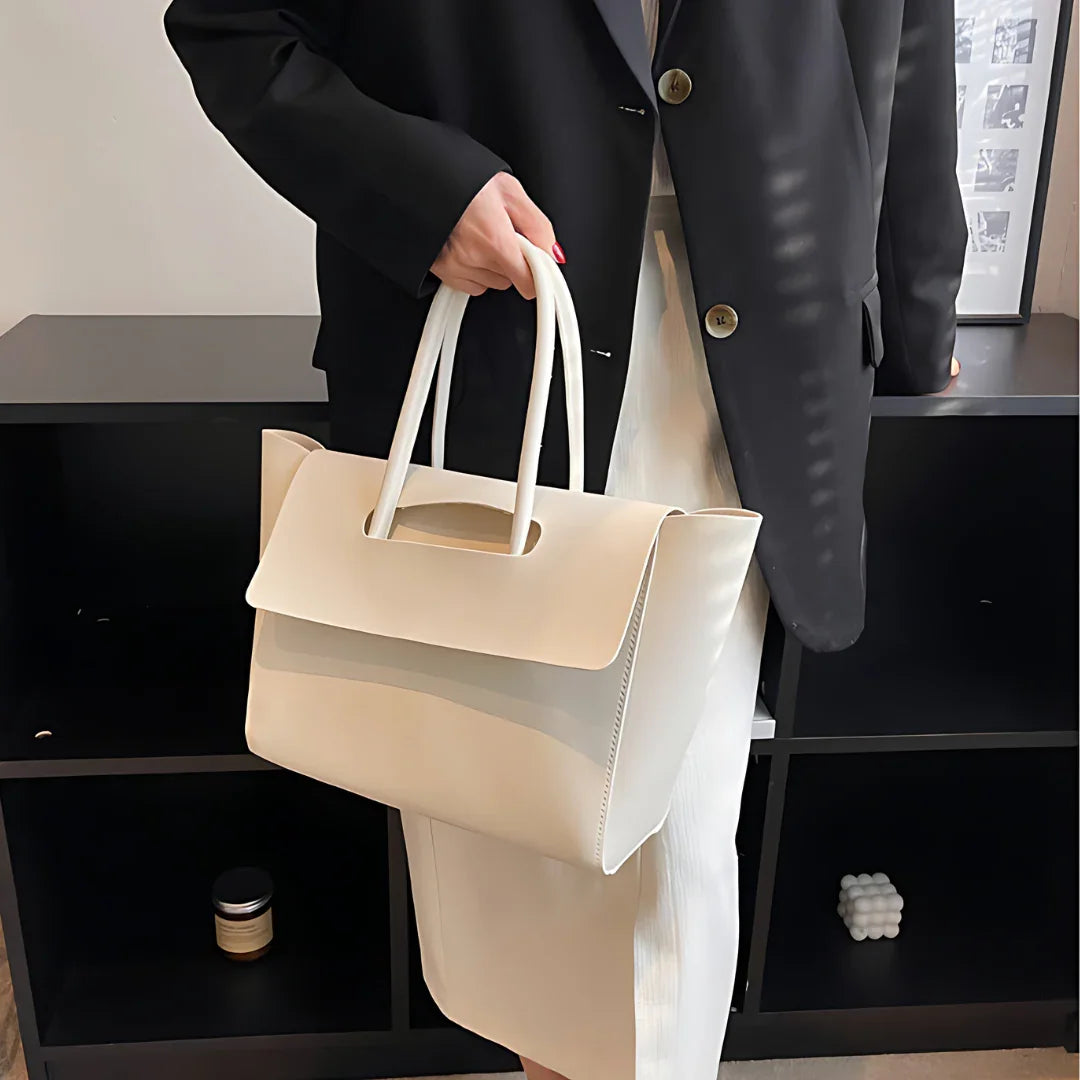 Woman in black blazer holding large white leather tote bag, modern minimalist style
