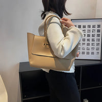 Woman wearing white jacket with beige leather tote bag, modern minimalist office decor