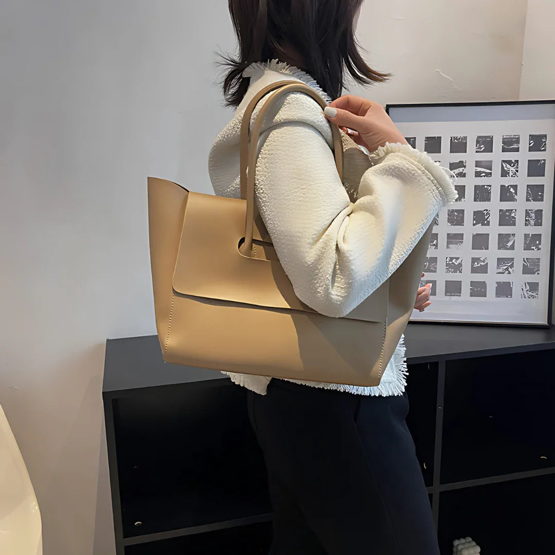 Woman wearing white jacket with beige leather tote bag, modern minimalist office decor