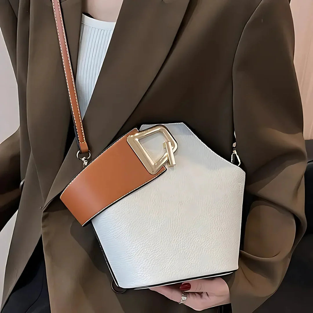 Woman wearing brown blazer holding geometric white leather handbag with wide tan strap