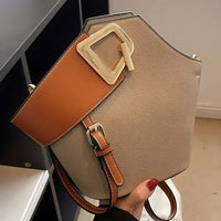 Stylish taupe leather handbag with wide brown strap and gold buckle, modern fashion accessory