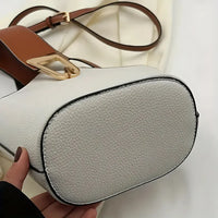 Close-up of white textured leather handbag with brown strap and gold buckle